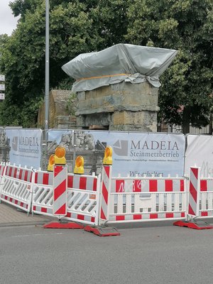 Foto des Torbogens am Jakobitor mit Absperrgittern und einem in eine Plane verpackten Gesims.