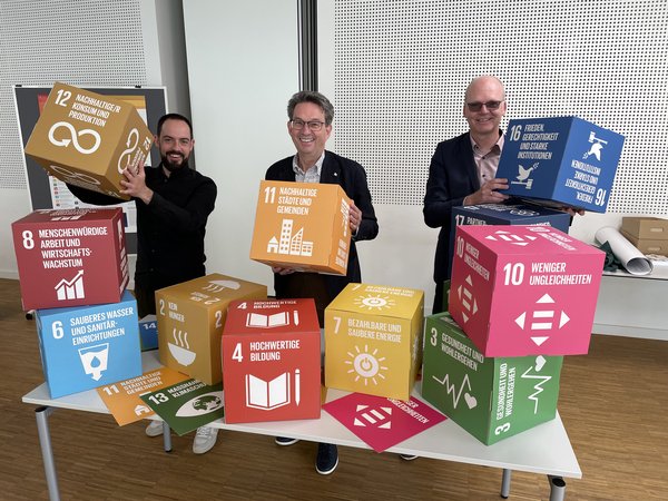 Bürgermeister Dr. Eckhard Ruthemeyer (Mitte) mit dem Gesamtverantwortlichen der Stadt Soest für Digitalisierung Jörg Radandt (rechts) und Smart-City-Projektmanager Stephan Siegert (links). Sie halten beispielhaft Würfel in den Händen, auf denen die 17 Nachhaltigkeitsziele der Vereinten Nationen benannt sind. 