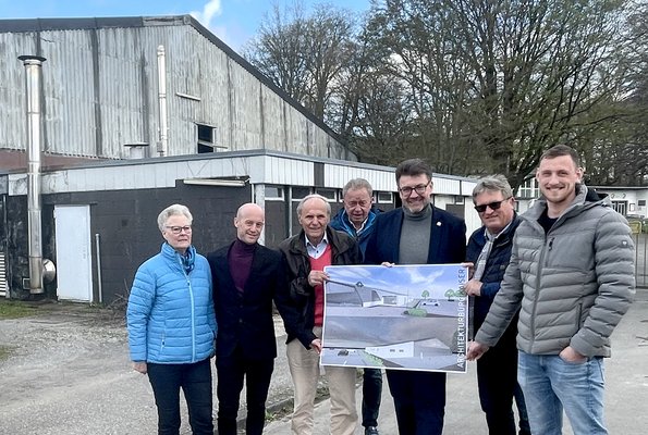 Vertreter der Tennisvereine und der Stadt Soest präsentieren vor der alten Tennishalle ein Computerbild des geplanten Teilneubaus.