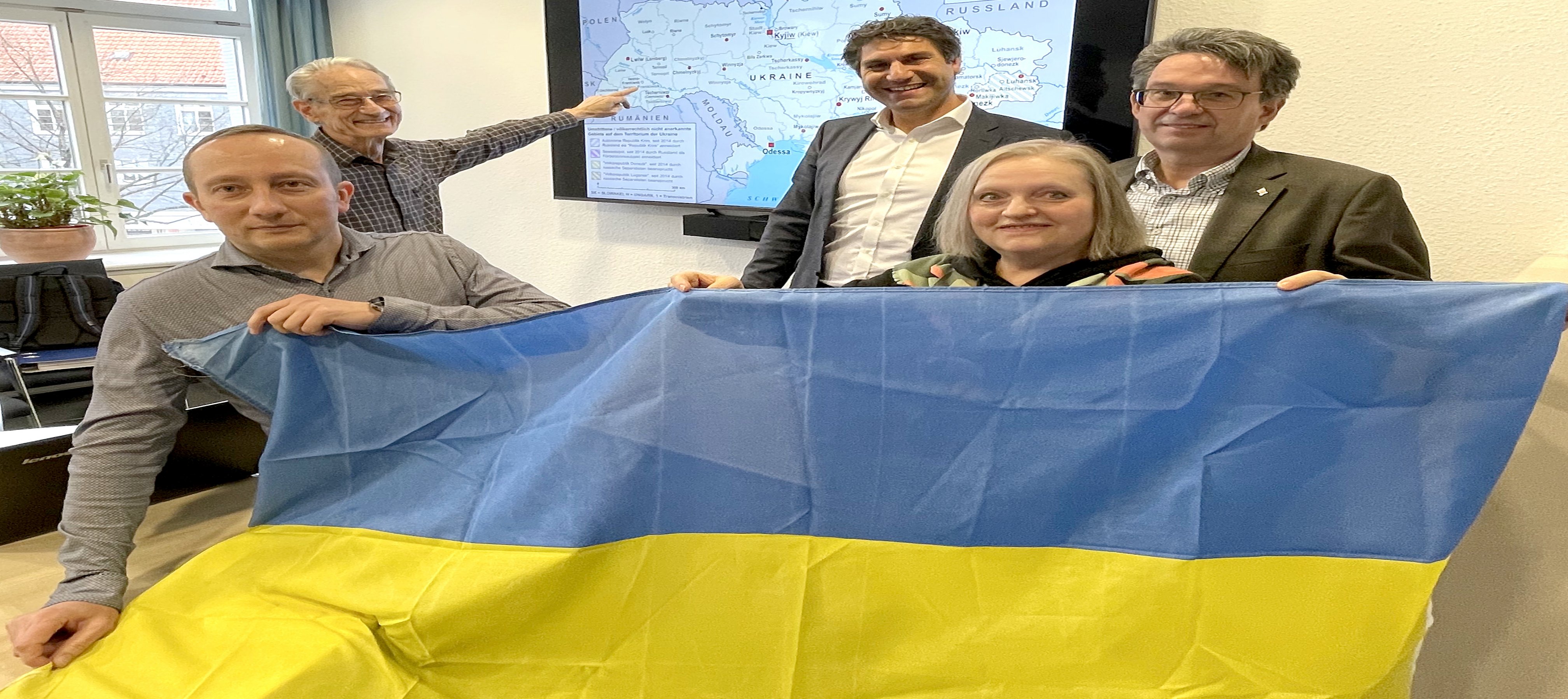 Oleksandr Rudenko, Wolfgang Ehlers, Christian Schug, Marina Zaslavskaya und Dr. Eckhard Ruthemeyer stehen mit einer ukrainischen Landesflagge in den Händen vor einer Landkarte der Ukraine. 