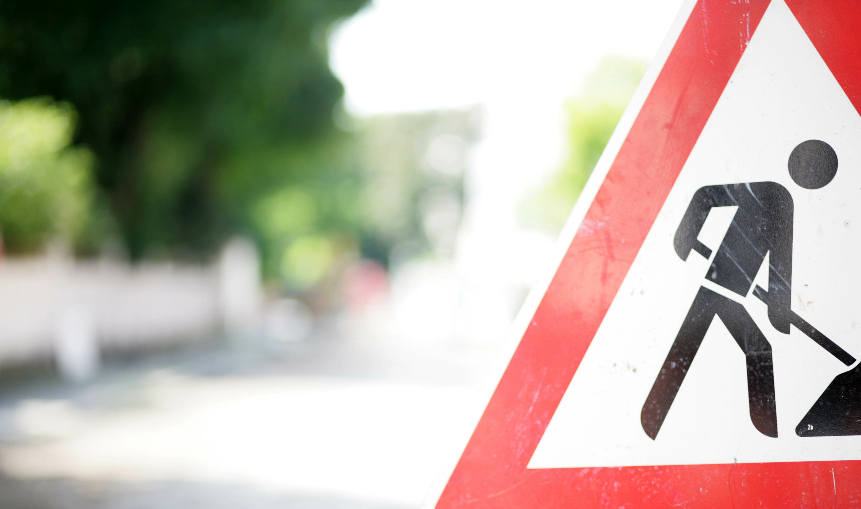 Foto eines Verkehrsschilds "Achtung Baustelle" am Rand einer Straße