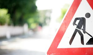 Foto eines Verkehrsschilds "Achtung Baustelle" am Rand einer Straße