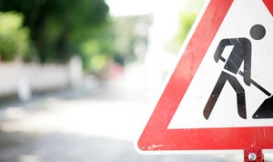 Foto eines Verkehrsschilds "Achtung Baustelle" am Rand einer Straße