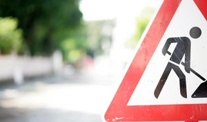 Foto eines Verkehrsschilds "Achtung Baustelle" am Rand einer Straße