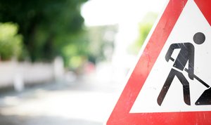 Foto eines Verkehrsschilds "Achtung Baustelle" am Rand einer Straße