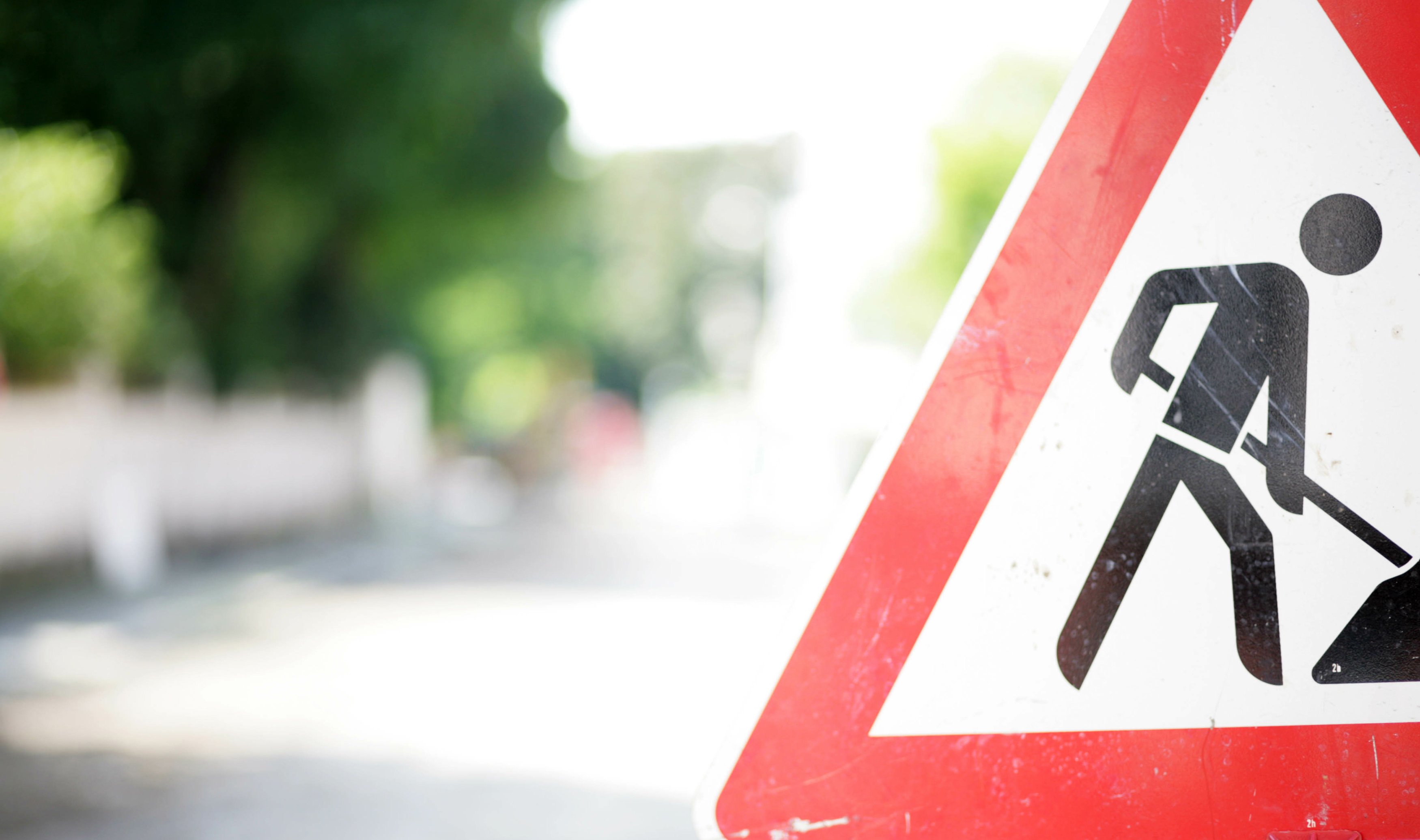 Foto eines Verkehrsschilds "Achtung Baustelle" am Rand einer Straße