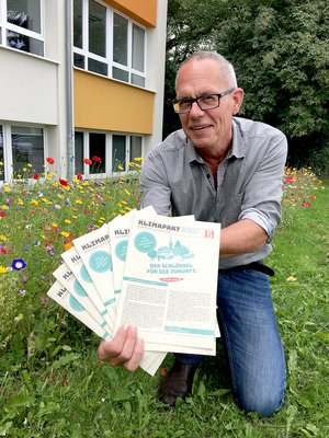 Klimaschutzbeauftragter hält Klimaschutzbroschüre in der Hand.