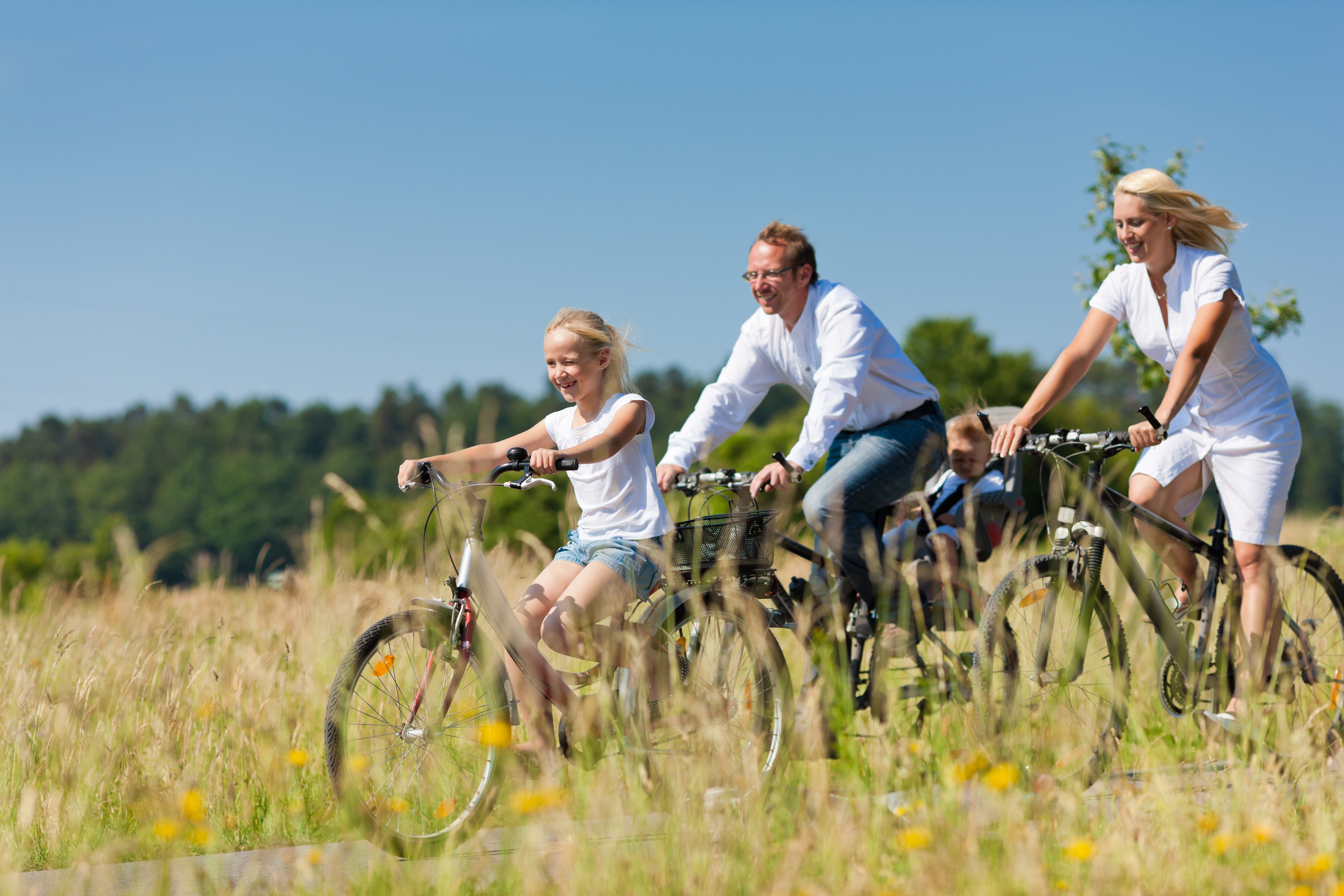 Fahrradfahrende Familie auf einem Feldweg zwischen sommerlichen Getreidefeldern